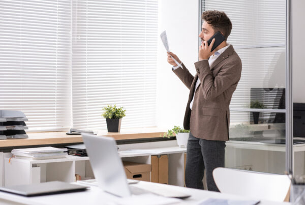 homme au téléphone qui tient une feuille