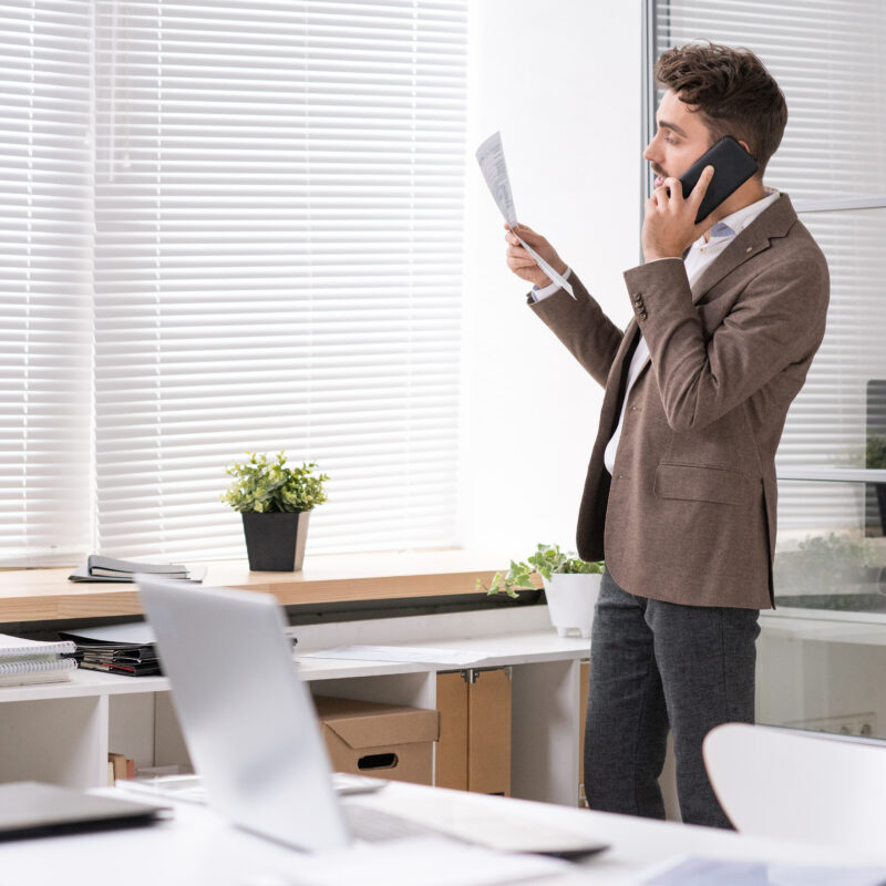 homme au téléphone qui tient une feuille