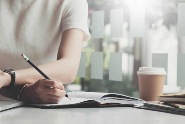 Une femme assise à son bureau qui remplit des documents manuellement