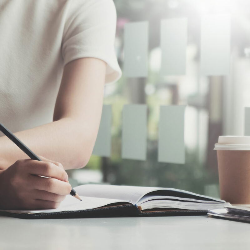 Une femme assise à son bureau qui remplit des documents manuellement